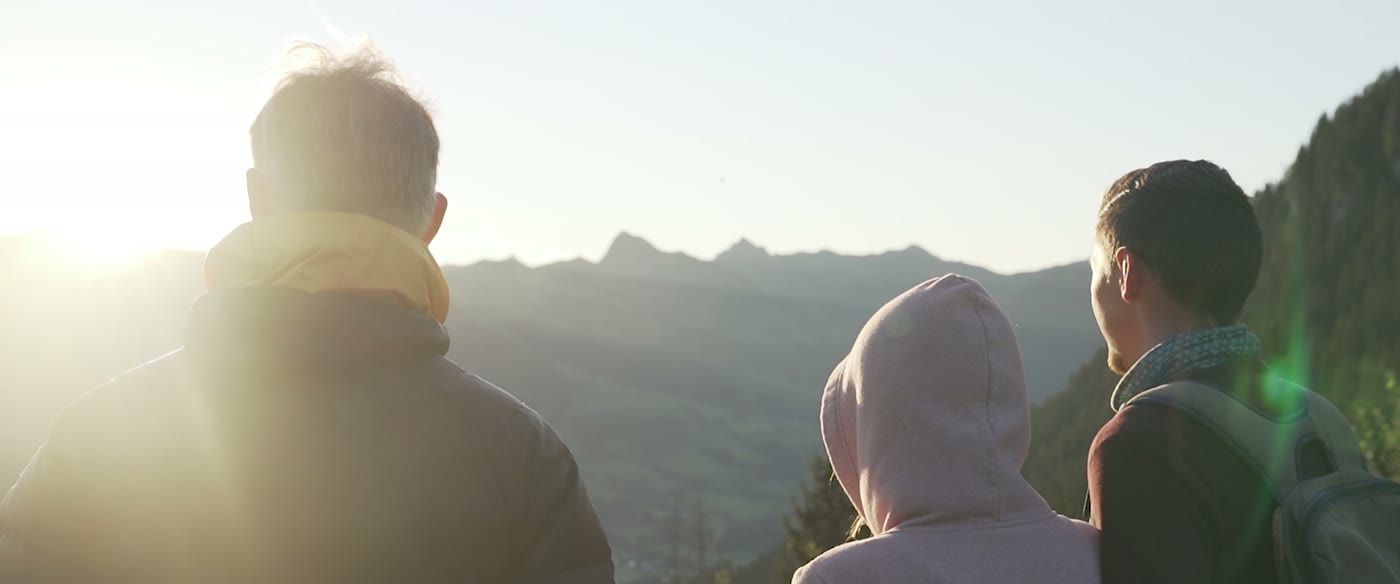 Wanderer im Gegenlicht auf einer Alm bei Sonnenuntergang
