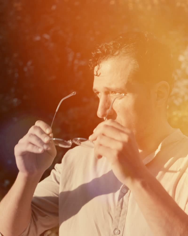 Mann im Gegenlicht setzt seine Brille ab